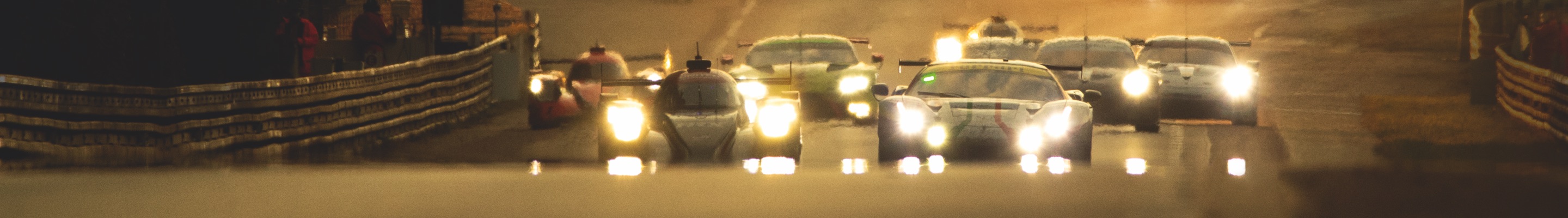 Le-Mans motorsports cars with headlights on, driving on race track