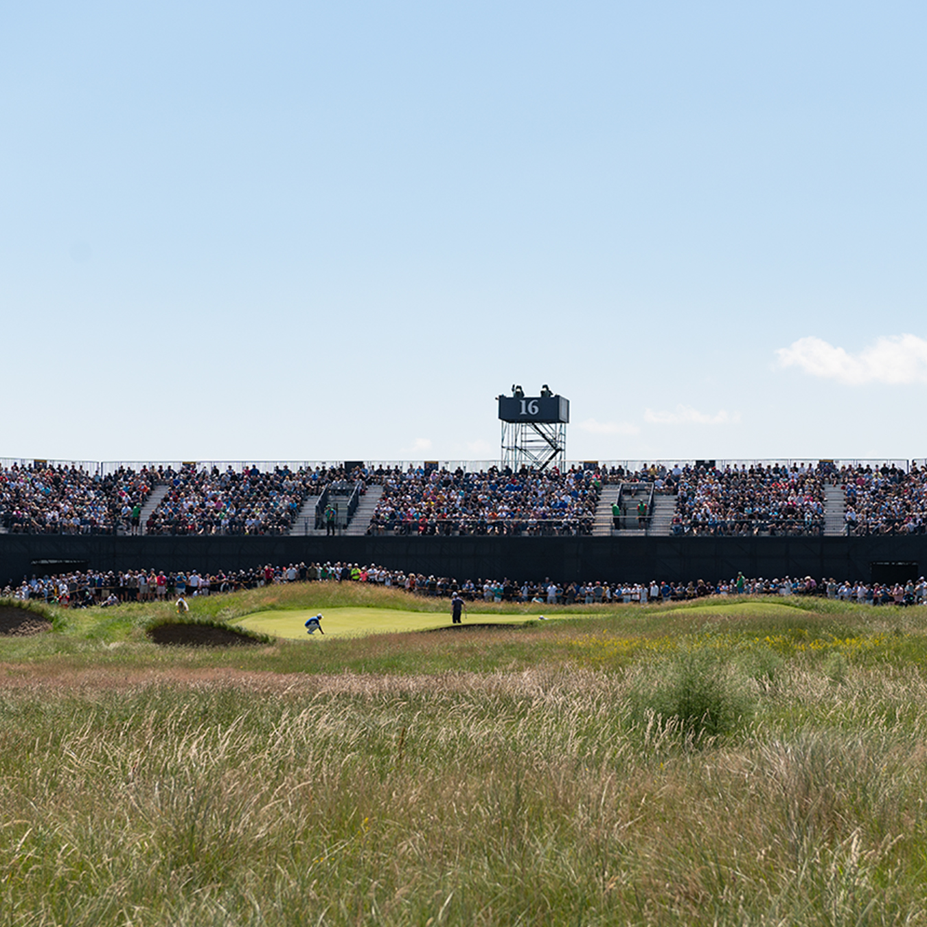 Golf tournament taking place, spectator seating in background