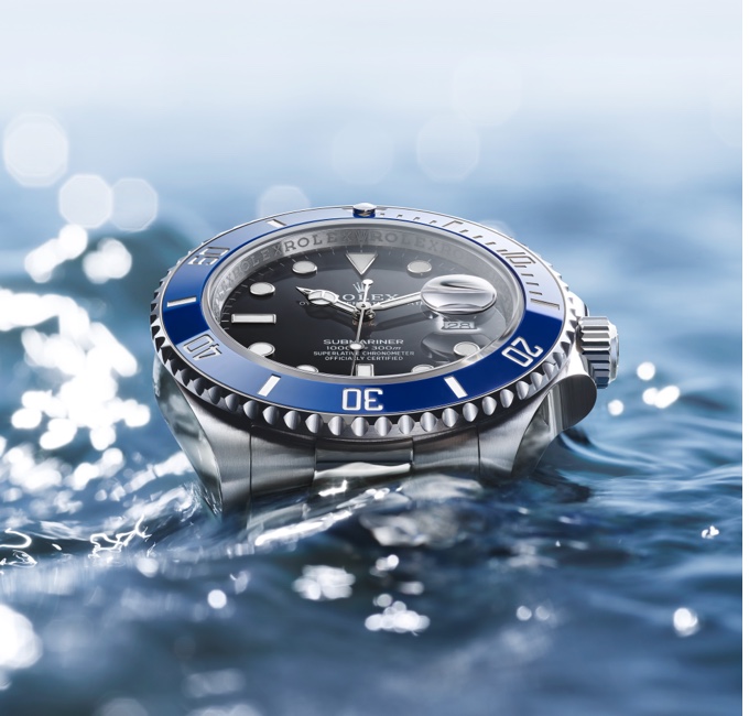 Silver Rolex Oyster Perpetual with black dial and navy detail in water