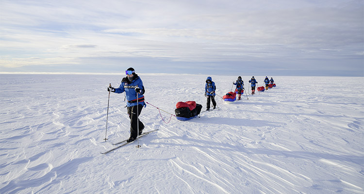Explorers pulling sleds through snowy landscape