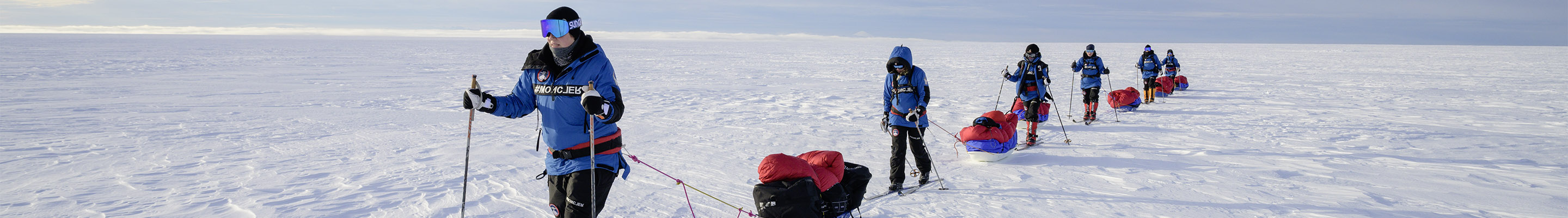 Explorers pulling sleds through snowy landscape