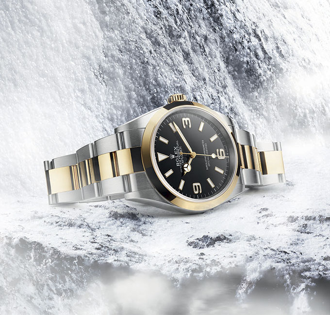 Two-tone Rolex watch with black dial on snowy background