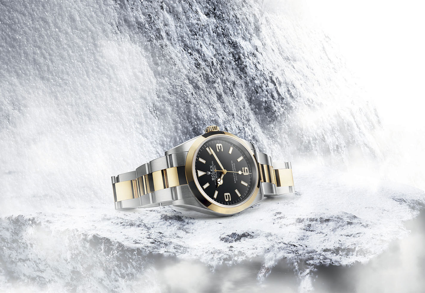Two-tone Rolex watch with black dial on snowy background