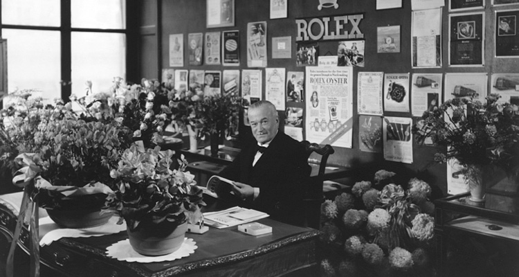 Hans Wilsdorf with Rolex logo in background