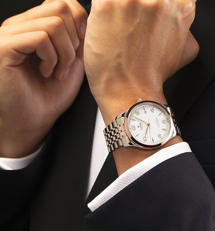 Silver Tudor watch on wrist with silver link strap and rose gold detail