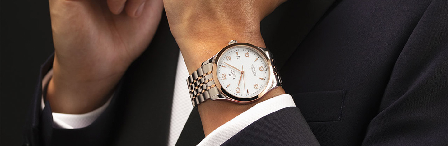 Silver Tudor watch on wrist with silver link strap and rose gold detail
